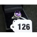 An attractive dress ring, stamped 14K, claw set with an oval amethyst within a border of tiny
