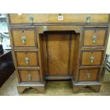 A Georgian style kneehole desk in mahogany and satinwood, with a slide above seven drawers around