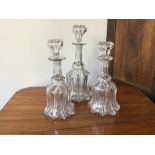 Three 19th century moulded glass decanters of bell shape, with stoppers, largest 14 cm diameter x 34