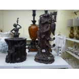 An impressive Chinese carved figure of an Immortal, probably in rosewood, carrying a branch and
