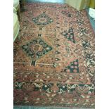 An Eastern rug, the red ground decorated overall with flowers and domestic items within multiple