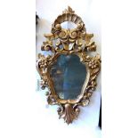An antique Continental carved and giltwood framed cartouche mirror with mercury glass, in baroque