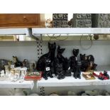 A shelf and a half of various cat figurines and ornaments including Bretby black cat, Royal Crown