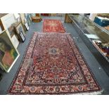 A Persian-style rug, the red ground decorated overall with vases of flowers within floral border;