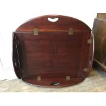 A mahogany butler's tray, oval with drop flaps, open 106 x 85 cm, closed 78 x 54.5 cm [This lot is