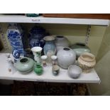 A shelf of pottery vases and jars plus a blue and white egg ornament, two pairs of china