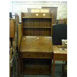 An upright desk in oak circa 1900 with a bookcase beneath a pierced border above the bureau, a