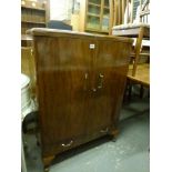 A 1960s walnut bar cabinet by Turnidge the hinged top opening for serving above an illuminated