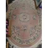 A pretty bedroom carpet, possibly Chinese, of oval form, the pink ground decorated with blue and