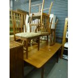 A 1970s teak dining room suite comprising an extending rectangular table and six slat back chairs (