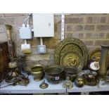Three shelves of various brassware including planters, ornaments, horse brasses on straps, vases,