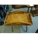 A vintage oval butler's tray, on a later folding stand to form a coffee table WE DO NOT ACCEPT