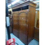 A handsome reproduction mahogany wardrobe, the pair of panel doors enclosing hanging and shelved