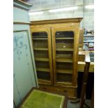 A tall bookcase in maple, Victorian with alterations, the pair of glazed doors above a long drawer