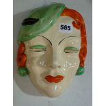 A Clarice Cliff Bizarre wall mask of a lady's head, wearing a stylish hat, in green, orange and