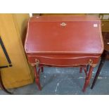 A charming French bureau painted in ox-blood red with gilt highlights, the fall enclosing a fitted