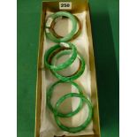 Five Oriental jadeite bangles in tones of bright green, three plain and two carved, and two multi-