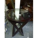 A modern circular occasional table with a glass-panel top on X-shaped supports, two old rowing