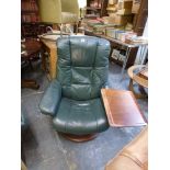 A modern revolving armchair in green leather, fitted with a reading table and matching footstool. WE