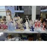 A shelf of decorative figurines including a Nao figure of a lady in a dark blue dress and another of