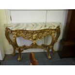 An elaborate Continental console table in carved and pierced gilt wood beneath a faux marble top. WE