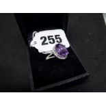 A white gold dress ring, presumed 14 ct, claw-set with an amethyst within a surround of tiny white