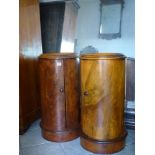 A pair of English pot cupboards of cylindrical form in figured walnut, beneath marble tops. WE DO