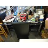 A modern glass-topped kitchen table on chrome supports, four modern chairs with black leather covers