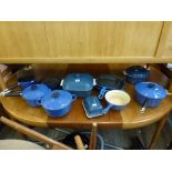 A set blue enamel Le Creuset kitchen items that includes frying pans, sauce pans, casserole