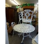 A garden metal table of circular pierced form on scrolling supports and four matching chairs, two of