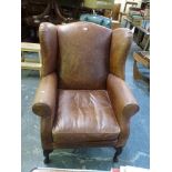 A substantial wing-back armchair in brown leather. WE DO NOT ACCEPT CREDIT CARDS. CLEARANCE DEADLINE