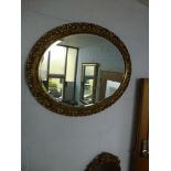 An oval gilt-framed bevel-edged mirror with pierced floral decoration, plus another gilt-framed wall