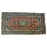 A Kashan rug with salmon pink ground, central dark blue and cream floral medallion with pendant