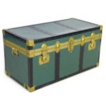 A vintage steamer trunk, green painted metal with brass accents, with retro paper lining to