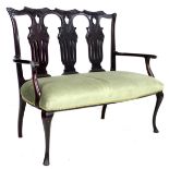 An Edwardian mahogany two seater salon settee, with shaped top rail, lyre shaped backrests, green