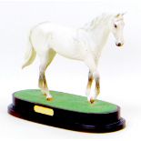 A Royal Doulton figurine of the racehorse Desert Orchid, raised upon a wooden plinth, 27 by 12 by