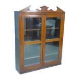 A late Victorian mahogany display cabinet, with carved pediment, twin glazed doors, three adjustable