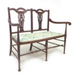 An Edwardian mahogany salon settee, with pierced splats, fabric covered seat, raised on slender