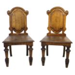 A pair of Victorian oak hall chairs, with fielded panel backs, raised on lobe carved front legs