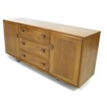 An Ercol solid Elm sideboard, with three central drawers flanked by two cupboards, all with oval