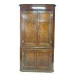 A George III oak and mahogany corner cupboard, floor-standing, with panelled doors and shelved