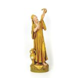 A Royal Dux figurine of a middle eastern street entertainer, holding a snake aloft, with maker's