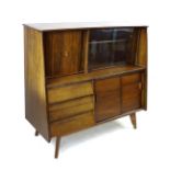 A retro teak sideboard cabinet, with glass sliding doors over a bank of three drawers, raised on