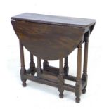 A 17th century oak drop leaf table, with oval surface, twin gate leg action, pegged joints, raised