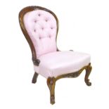 A Victorian mahogany nursing chair, carved frame, upholstered in pink fabric, raised on cabriole