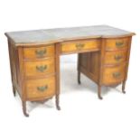 A Continental fruitwood writing desk, with green leatherette surface, seven drawers with brass plate