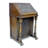 A Victorian oak writing desk, of narrow form with slope front carved with scrolling foliage, opening