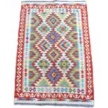 A vegetable dye Chobi Kilim rug, featuring a colourful geometric design to its centre, with orange