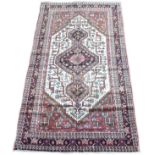 A Toserkan rug with a pink/brown ground, with a black diamond medallion with pendant anchors on a