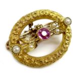 An 18ct gold, ruby and pearl brooch, of textured open oval design with central ruby of 3mm diameter,